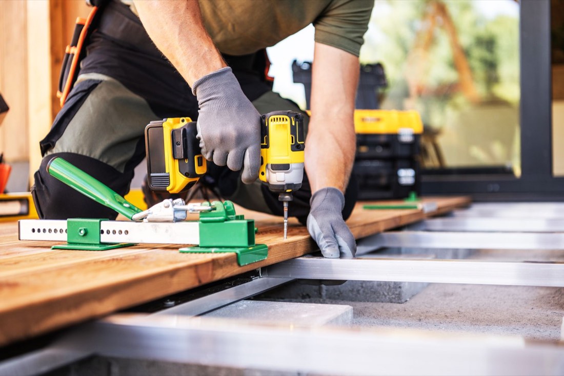 Builder fastening composite deck boards to the frame with a drill