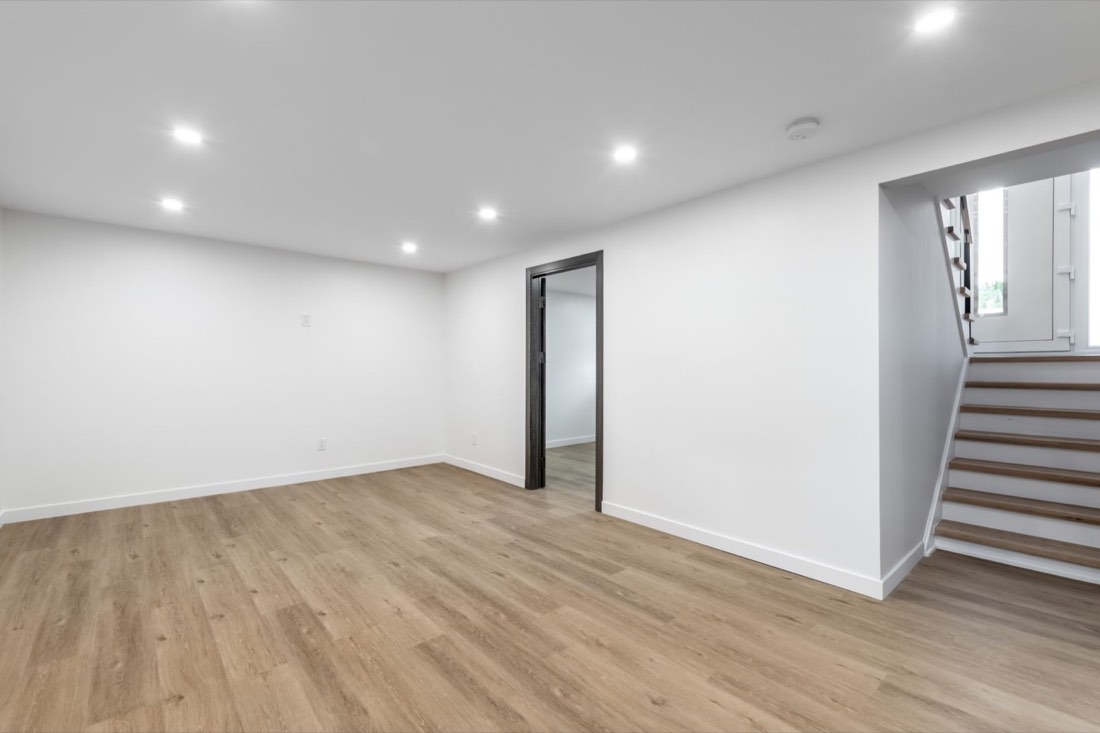 Finished basement with light wood flooring, recessed lighting, and a staircase