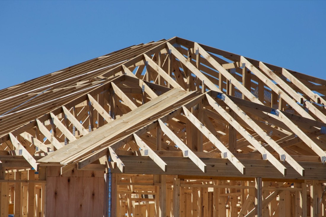 Roof trusses framed over a new home extension against a blue sky
