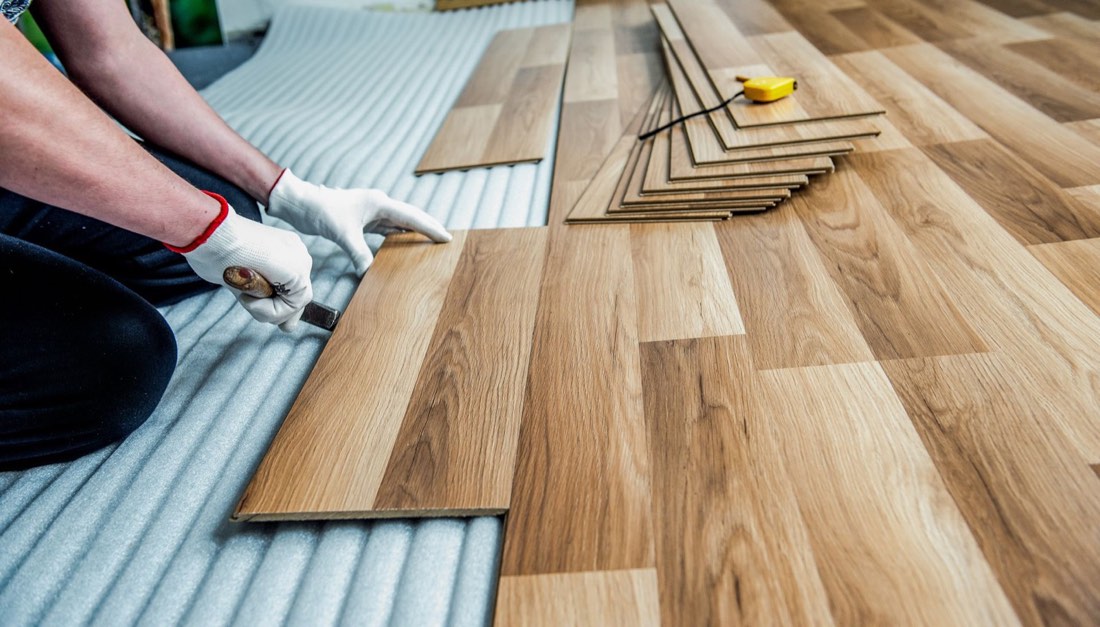 Installer fitting wood-look plank flooring over underlayment