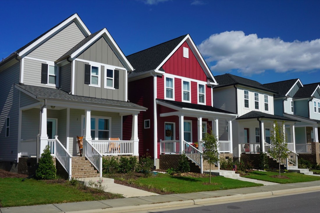 Row of colorful two-story homes with front porches on a suburban street