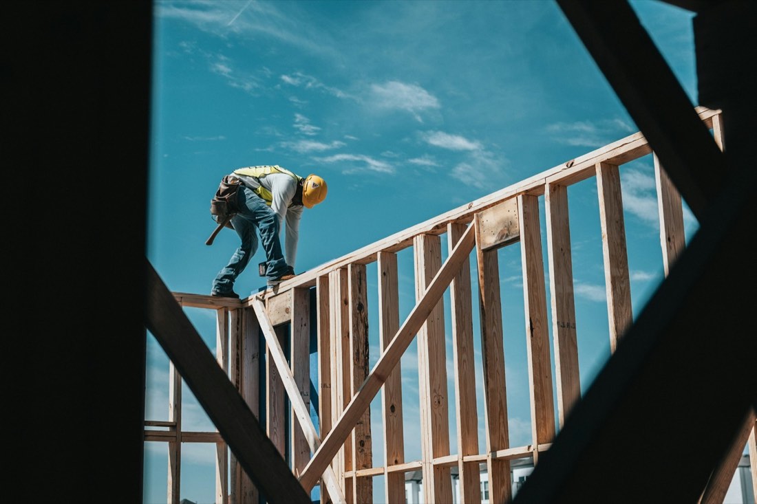 Carpenter in a hard hat framing the walls of a second-floor addition