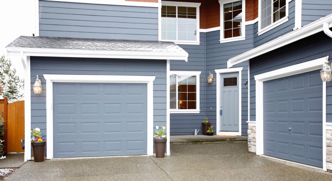 Two-story home with new blue siding, white trim, and matching garage doors